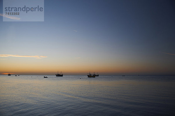 Boote auf ruhigem Wasser bei Sonnenuntergang