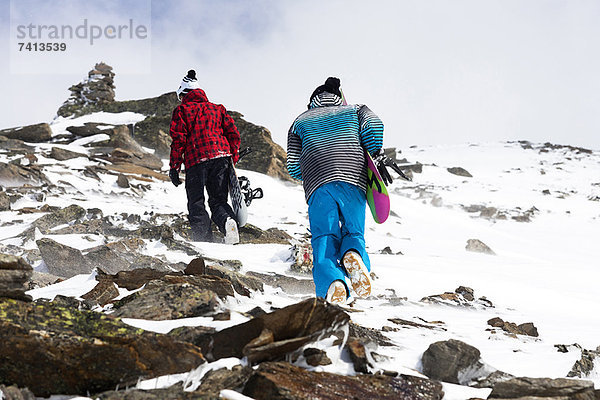 Snowboarder beim Wandern auf felsigen Pisten