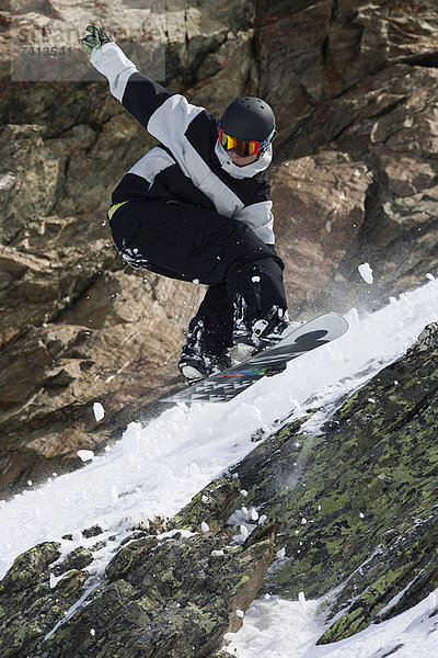 Snowboarder springen auf felsiger Piste
