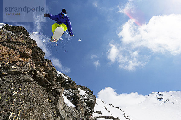 Snowboarder springen auf felsiger Piste