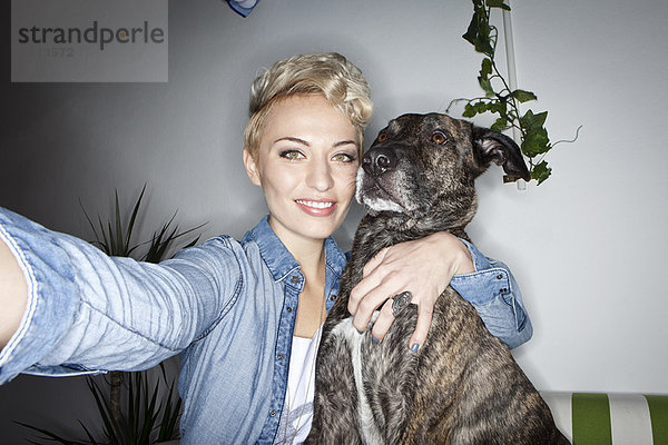 Lächelnde Frau beim Fotografieren mit Hund