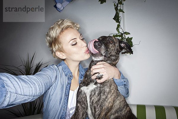 Lächelnde Frau beim Fotografieren mit Hund