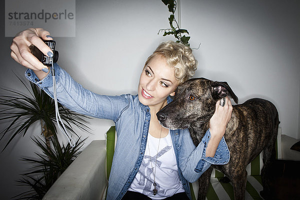 Lächelnde Frau beim Fotografieren mit Hund