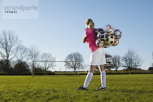 Fußballspieler mit Bällen im Feld