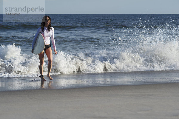 Frau mit Surfboard am Strand