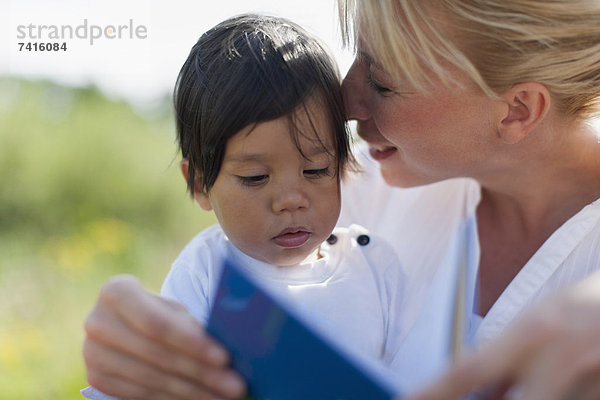 Außenaufnahme  Buch  Junge - Person  Taschenbuch  Mutter - Mensch  Baby  freie Natur  vorlesen