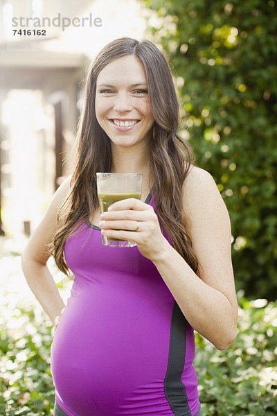 Portrait Frau Sport Glas grün halten Kleidung Schwangerschaft Mittelpunkt Saft Erwachsener