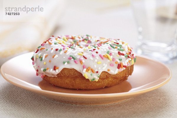 Ein Doughnut mit Zuckerglasur und bunten Zuckerstreuseln
