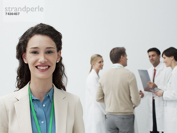 Porträt einer lächelnden Geschäftsfrau mit Ärzten im Hintergrund