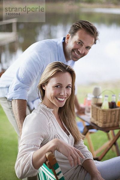 Porträt eines lächelnden Paares beim Picknick am Seeufer