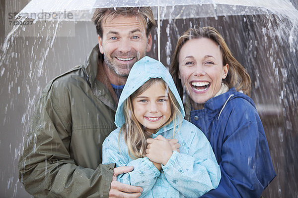 Porträt einer enthusiastischen Familie unter dem Regenschirm
