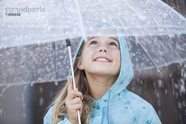 Nahaufnahme des lächelnden Mädchens unter dem Schirm im Regenschauer