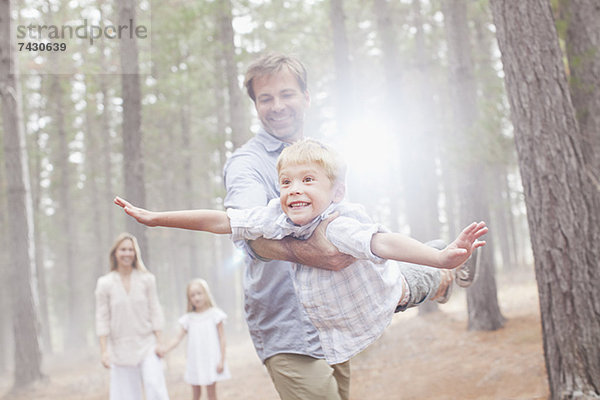 Vater fliegender Sohn im sonnigen Wald