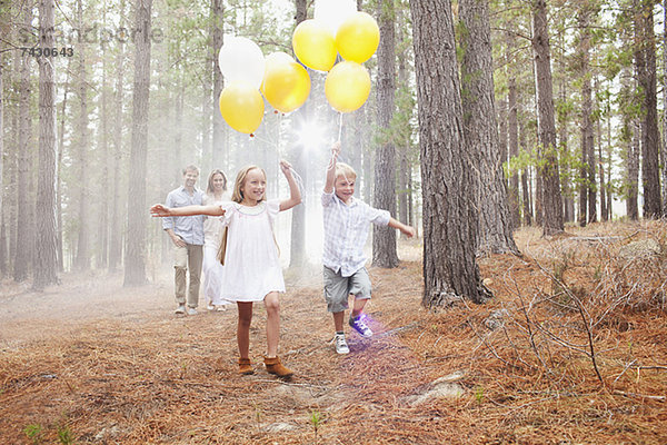 Glückliche Familie mit Ballons im Wald