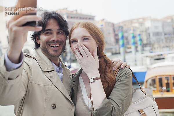 Lachendes Paar beim Selbstporträt mit Fotohandy in Venedig