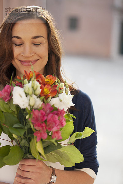 Lächelnde Frau riecht Blumenstrauß