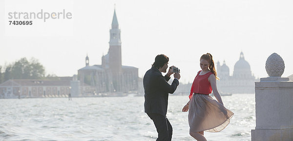 Mann filmt Frau am Wasser in Venedig