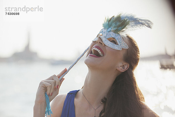 Lachende Frau mit Maske am Wasser in Venedig