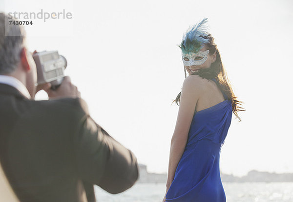 Mann filmt Frau mit Maske am Wasser in Venedig