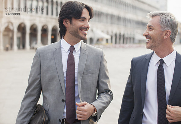 Lächelnde Geschäftsleute im Gespräch auf dem Markusplatz in Venedig