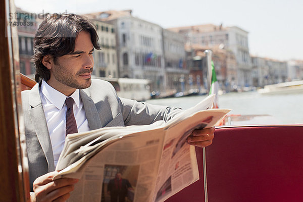 Geschäftsmann liest Zeitung auf dem Schiff in Venedig