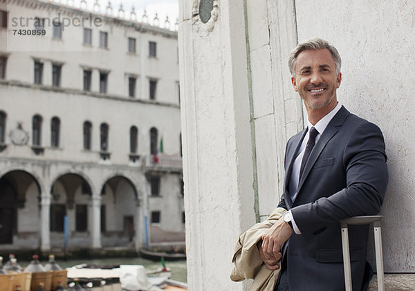 Porträt eines lächelnden Geschäftsmannes mit Koffer in Venedig