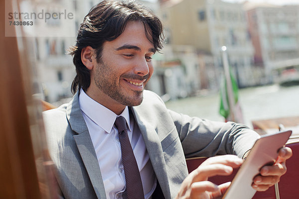 Lächelnder Geschäftsmann mit digitalem Tablett auf dem Schiff in Venedig