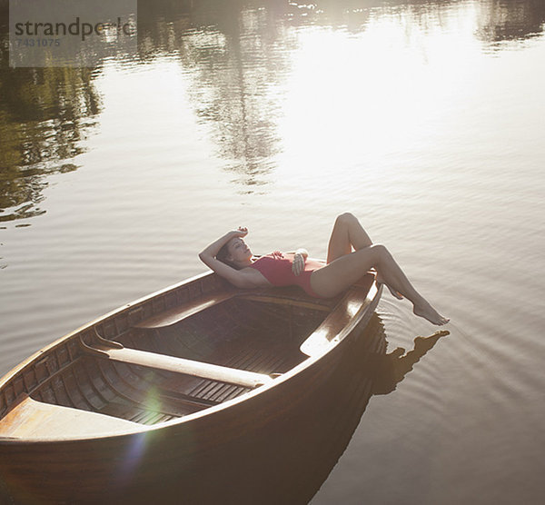 Gelassene Frau beim Sonnenbaden im Boot auf dem See