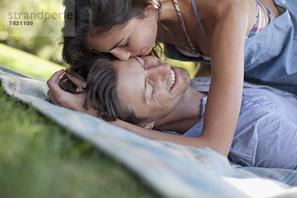 Liebespaar auf Decke im Gras liegend