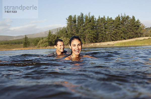 Porträt eines lächelnden Paares beim Schwimmen im See