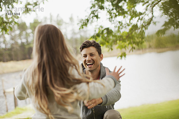 Tochter läuft mit ausgestreckten Armen auf lächelnden Vater zu.