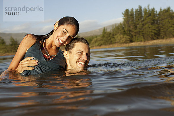 Porträt eines lächelnden Paares beim Schwimmen im See