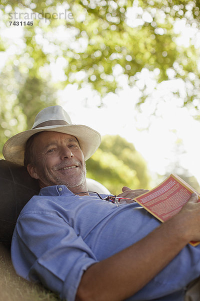 Porträt eines lächelnden Mannes im Gras mit Buch