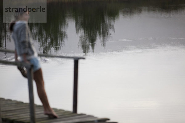 Frau auf dem Dock über dem See stehend