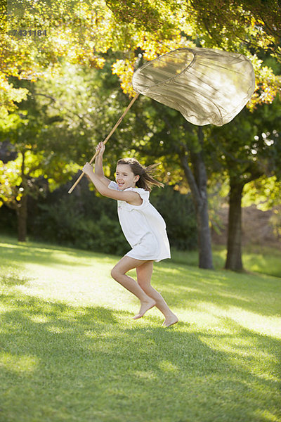 Glückliches Mädchen läuft mit Schmetterlingsnetz im Gras