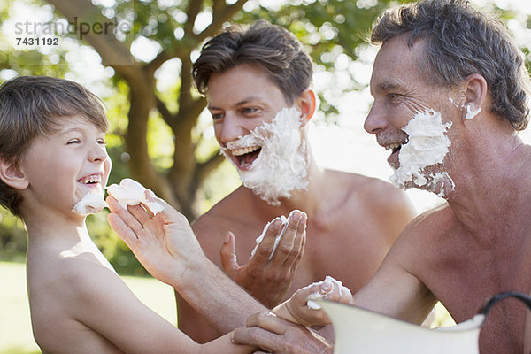 Verspielte Mehrgenerationen-Männer beim Auftragen von Rasiercreme auf Gesichter
