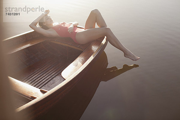 Gelassene Frau beim Sonnenbaden im Boot auf dem See