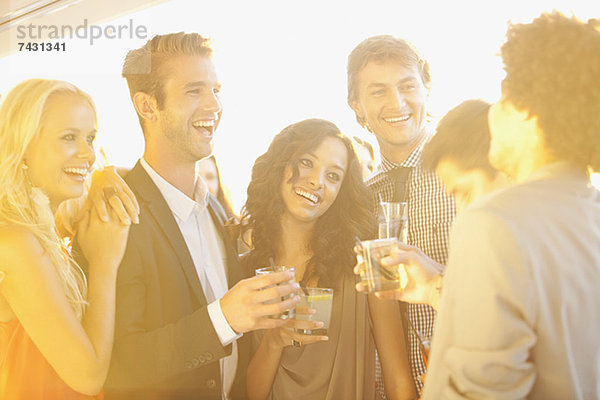 Lächelnde Freunde trinken Cocktails auf dem sonnigen Balkon