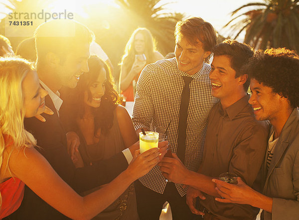 Freunde toasten Cocktails auf dem sonnigen Balkon