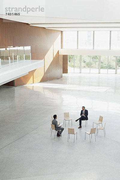Geschäftsleute sitzen am Stuhlkreis in der modernen Lobby