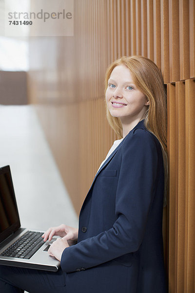 Portrait einer lächelnden Geschäftsfrau mit Laptop