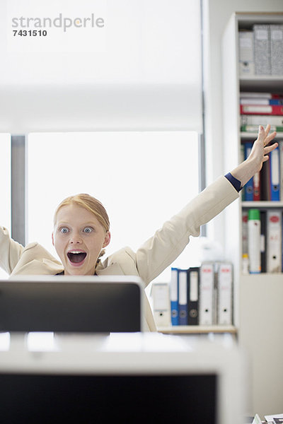 Überschwängliche Geschäftsfrau am Computer im Büro