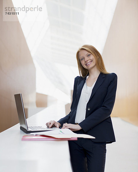 Porträt der lächelnden Geschäftsfrau mit Laptop im Büro
