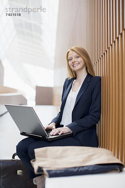 Portrait einer lächelnden Geschäftsfrau mit Laptop