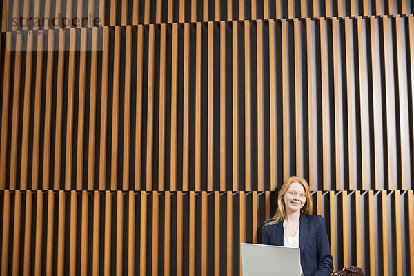 Portrait einer lächelnden Geschäftsfrau mit Laptop