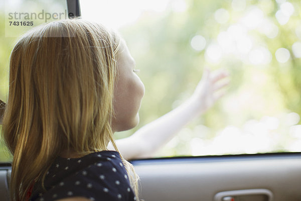 Mädchen  das aus dem Autofenster greift