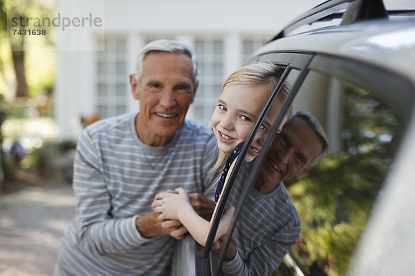 Älterer Mann im Gespräch mit Enkelin im Autofenster
