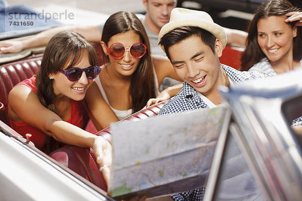 Freunde lesen Straßenkarte im Cabriolet