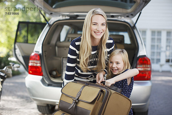 Mutter und Tochter tragen Gepäck zum Auto