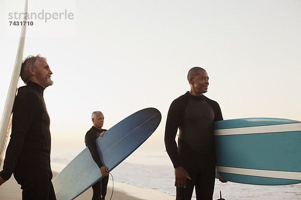 Ältere Surfer mit Brettern am Strand